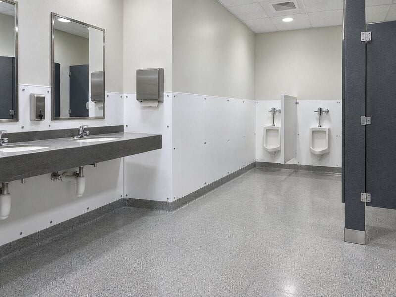 White bathroom wall panels installed as wainscoting along a commercial restroom wall with urinal stalls
