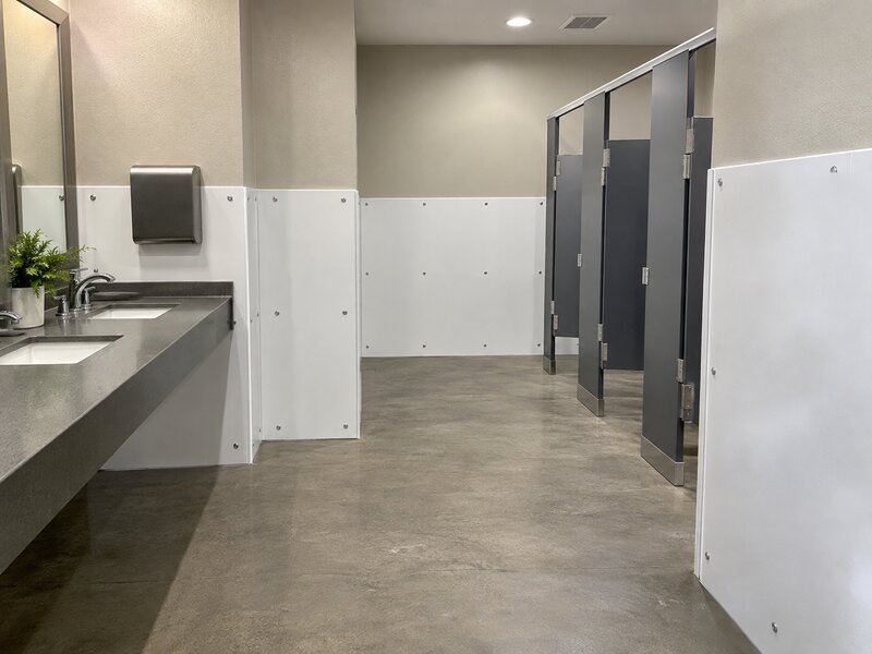 Bathroom wall panels installed along a vanity and stall hallway in a commercial restroom

