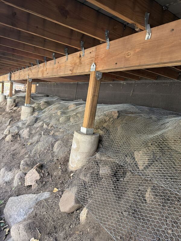 Burrowing rodent barrier mesh installed under a raised deck around pier footings

