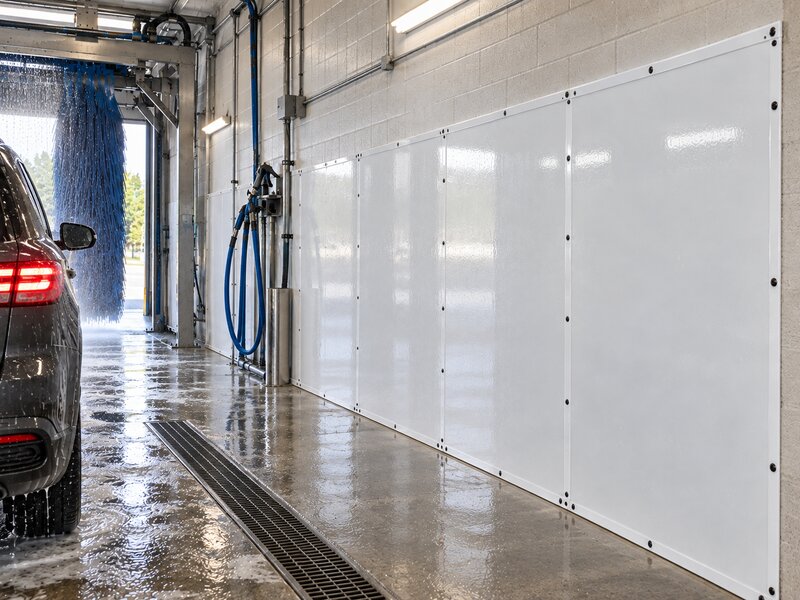 SUV exiting a wash bay lined with white HDPE car wash wall panels
