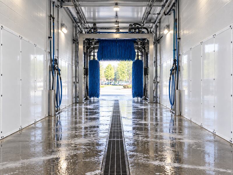 Car wash wall panels lining both sides of an automated brush tunnel wash bay
