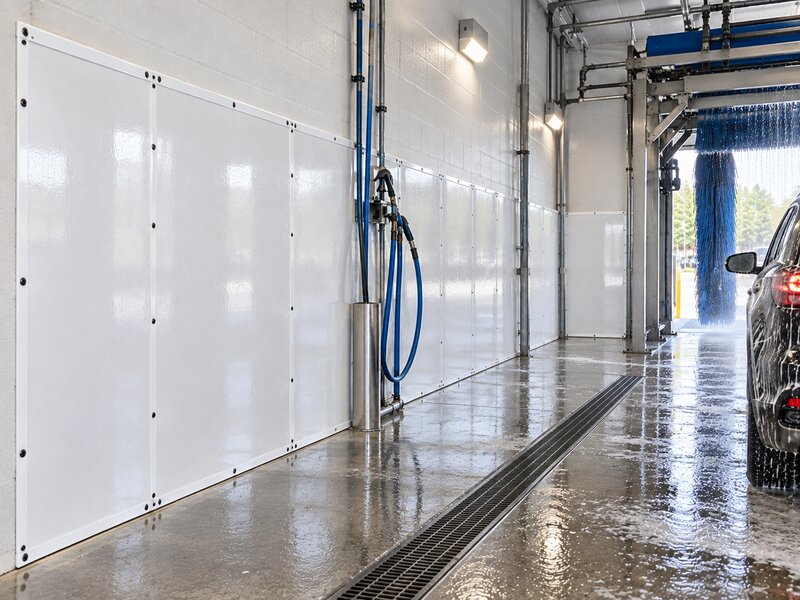 SUV being washed in an automated brush tunnel lined with car wash wall panels
