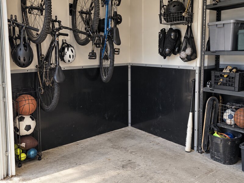 Garage corner with black HDPE wall liner behind hanging bikes and sports equipment storage

