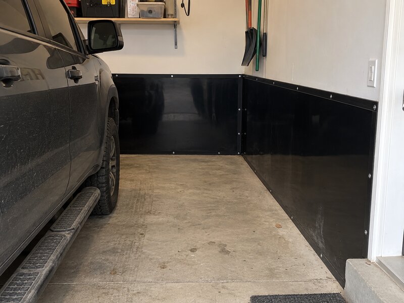 Garage parking bay with black HDPE wall liner installed along the walls beside a parked truck
