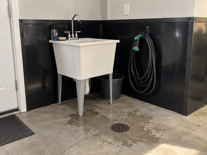 Utility sink area with black HDPE wall liner protecting the walls near a hose reel
