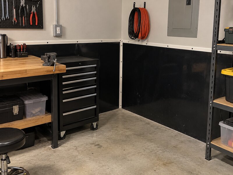 Garage workbench area with black HDPE wall liner behind a tool chest and electrical panel
