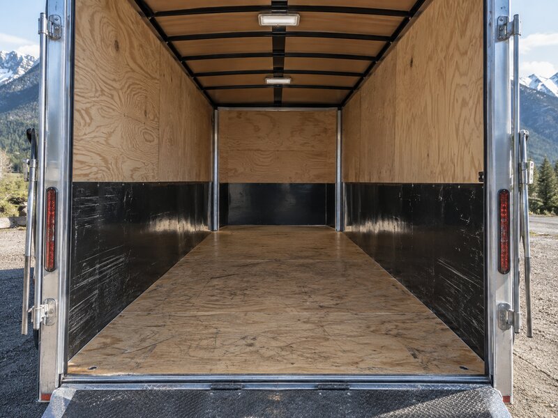 Enclosed trailer interior with HDPE wall liner on both walls, mountain view through open door
