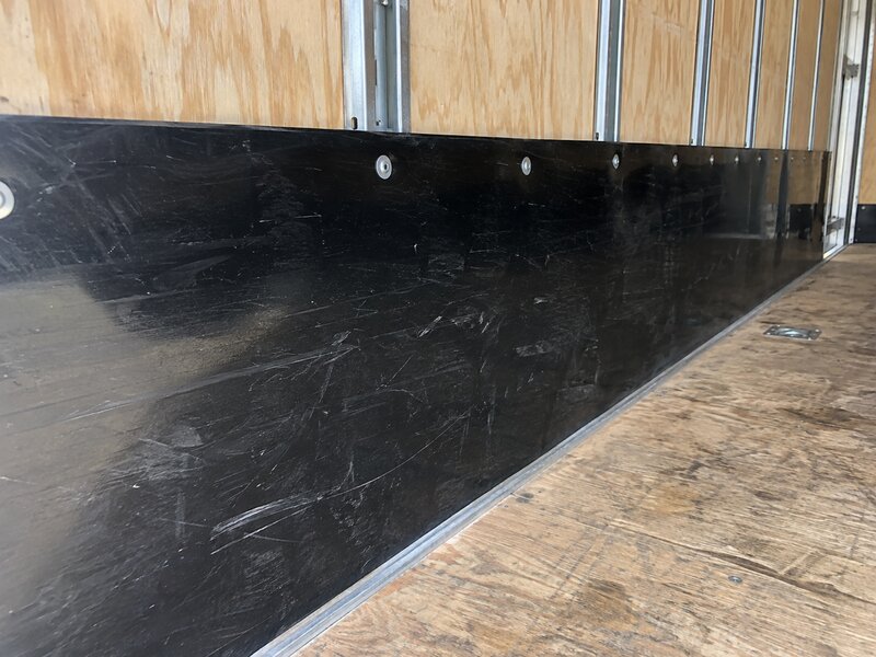 Close-up of a scratch-resistant black HDPE trailer wall liner panel riveted to plywood
