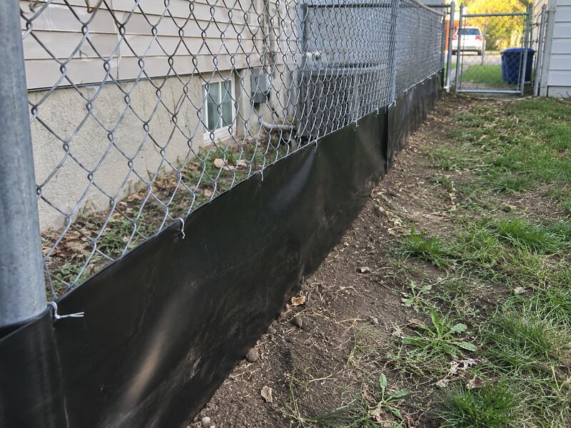 HDPE under fence barrier along a chain link fence near a driveway gate
