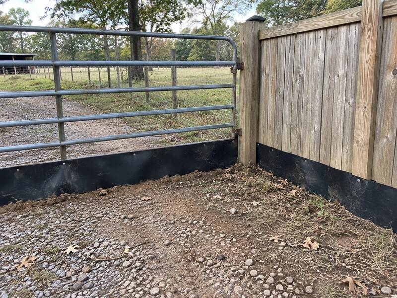 HDPE fence barrier installed at a farm gate and wood fence corner over a gravel driveway
