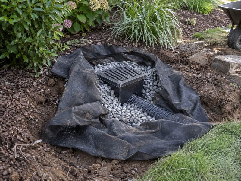Non-woven fabric lining a garden drain catch basin surrounded by gravel
