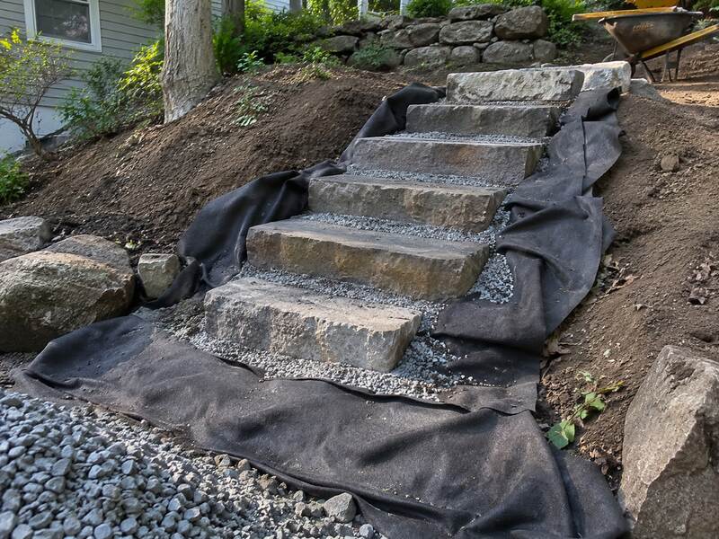 Non-woven fabric lining a hillside beneath a stone step staircase installation
