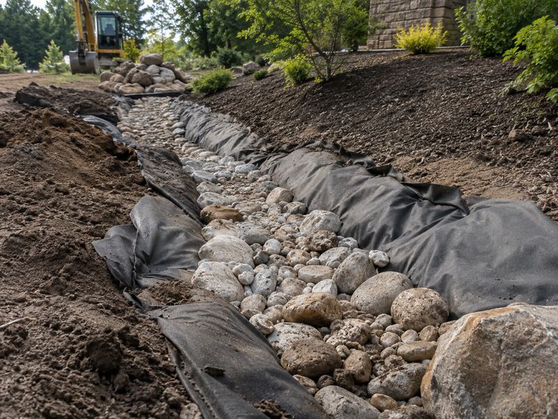 Non-woven geotextile fabric lining a dry creek bed rock channel landscape feature
