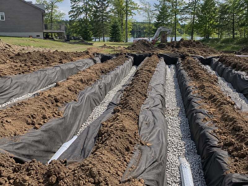 Non-woven geotextile fabric lining multiple leach field trenches filled with gravel and pipe
