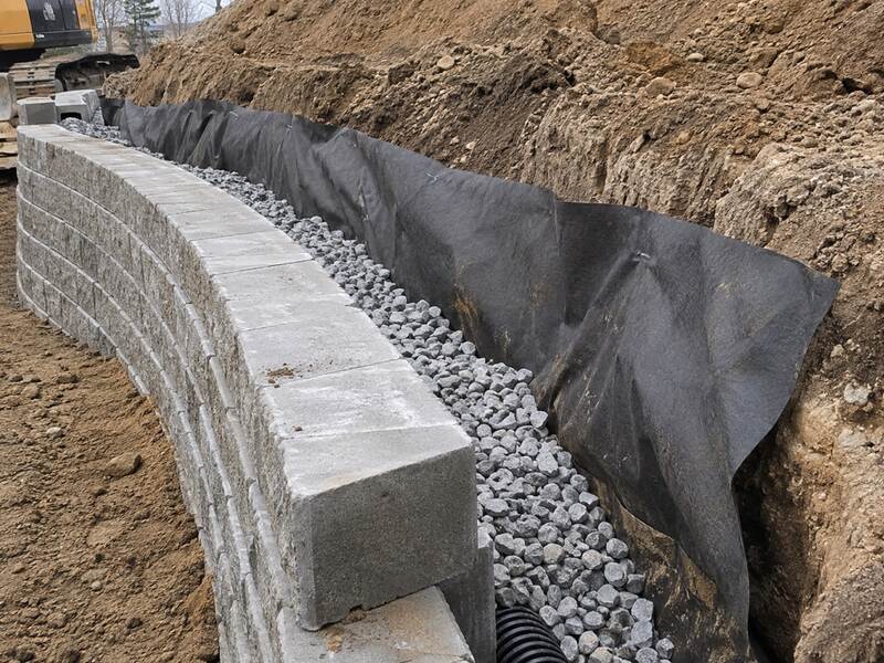 Non-woven geotextile fabric wrapping drainage gravel behind a block retaining wall
