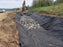 Non-woven geotextile fabric lining a roadside drainage ditch filled with rock
