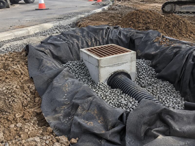 Non-woven geotextile fabric lining a storm drain inlet excavation with gravel
