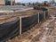 Silt fence installed around a muddy commercial parking lot construction site
