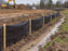 Silt fence lining a muddy drainage ditch at a rural construction site
