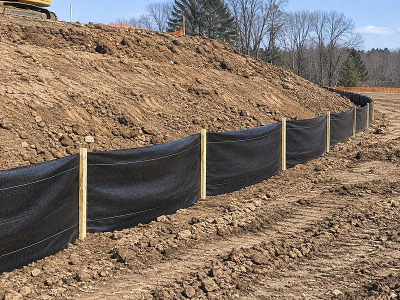 Silt fence installed along the base of a graded hillside slope for erosion control
