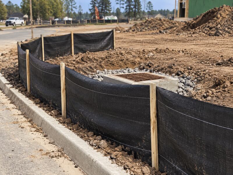 Silt fence protecting a storm drain inlet at a construction site curb
