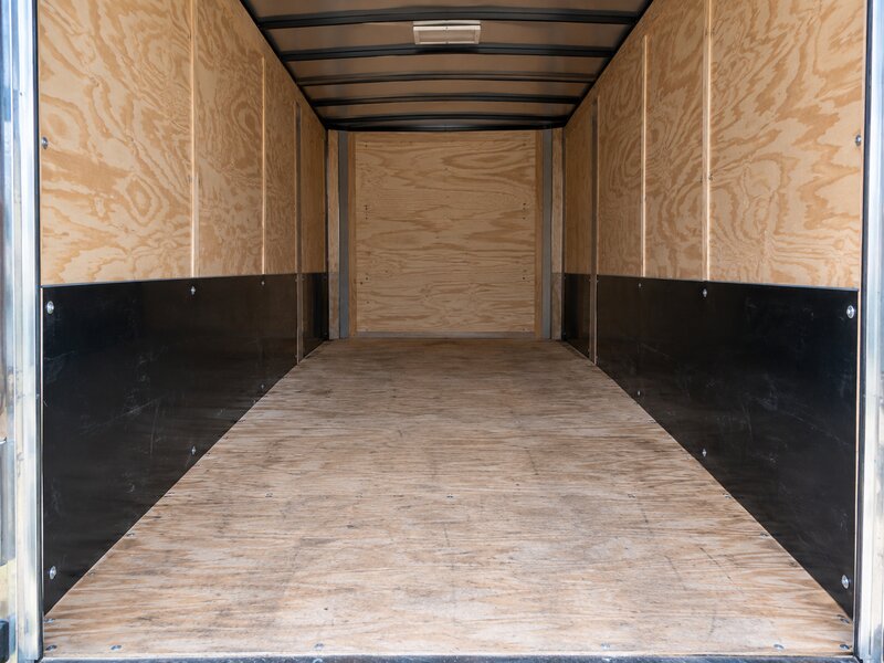 Empty cargo trailer interior with bare plywood walls before HDPE wall liner installation
