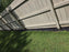 Black under-fence plastic barrier installed along the bottom of a wood privacy fence
