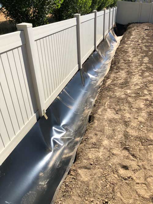 The waterproof ditch liner installed along a fenceline.