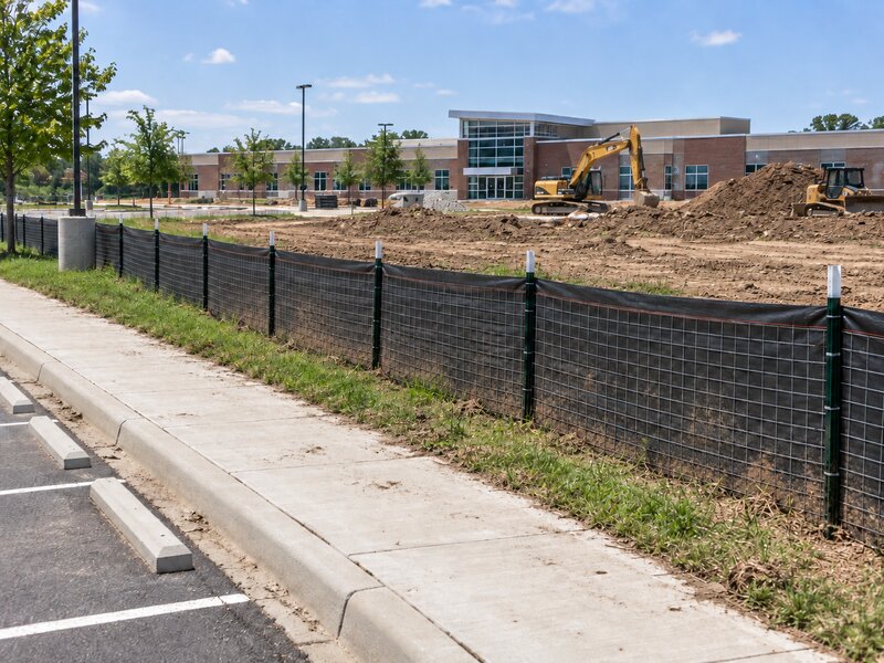 Wire backed silt fence installed along a sidewalk at a commercial building construction site
