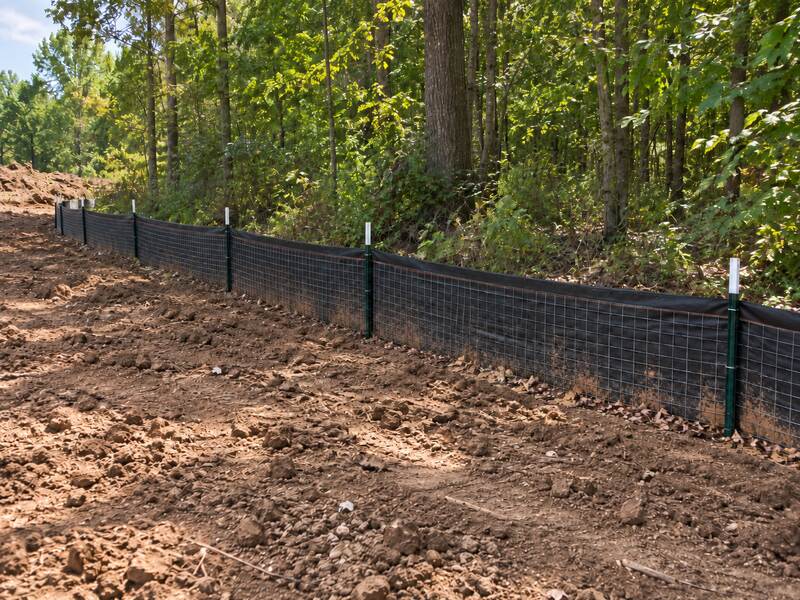 Wire backed silt fence installed along a wooded hillside grading site
